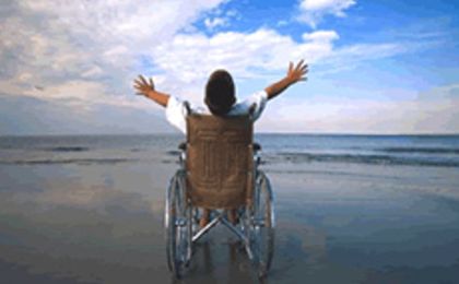 Immagine: foto di studente disabile in carrozzina davanti al mare che alza le braccia