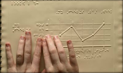 Immagine: foto di mani di bambino che leggono un testo in Braille